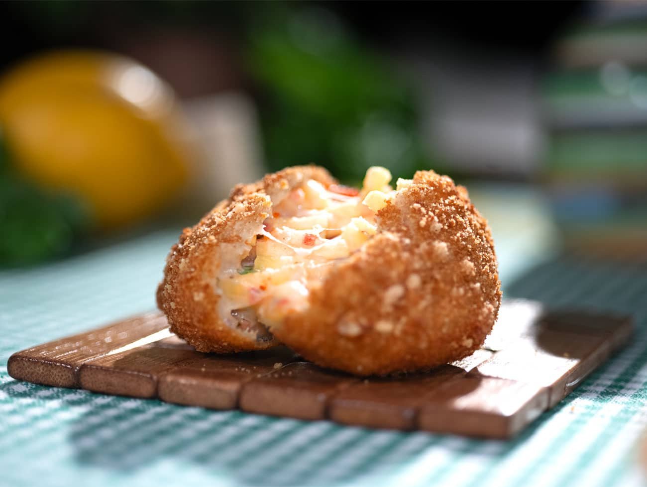 La frittatina Napoletana è poggiata su un piccolo supporto di legno poggiato a sua volta su una tovaglia a quadretti bianca e celeste