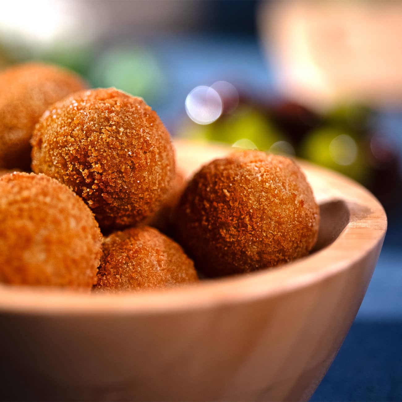 produzione fritti artigianali. Foto del dettaglio delle olive ascolane viste da vicino. Le olive ascolane dorate e croccanti sono inserite in una ciotola di legno.