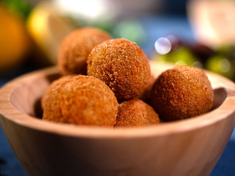 Foto del dettaglio di una piccola ciotola di legno ripiena di olive ascolane dorate e croccanti
