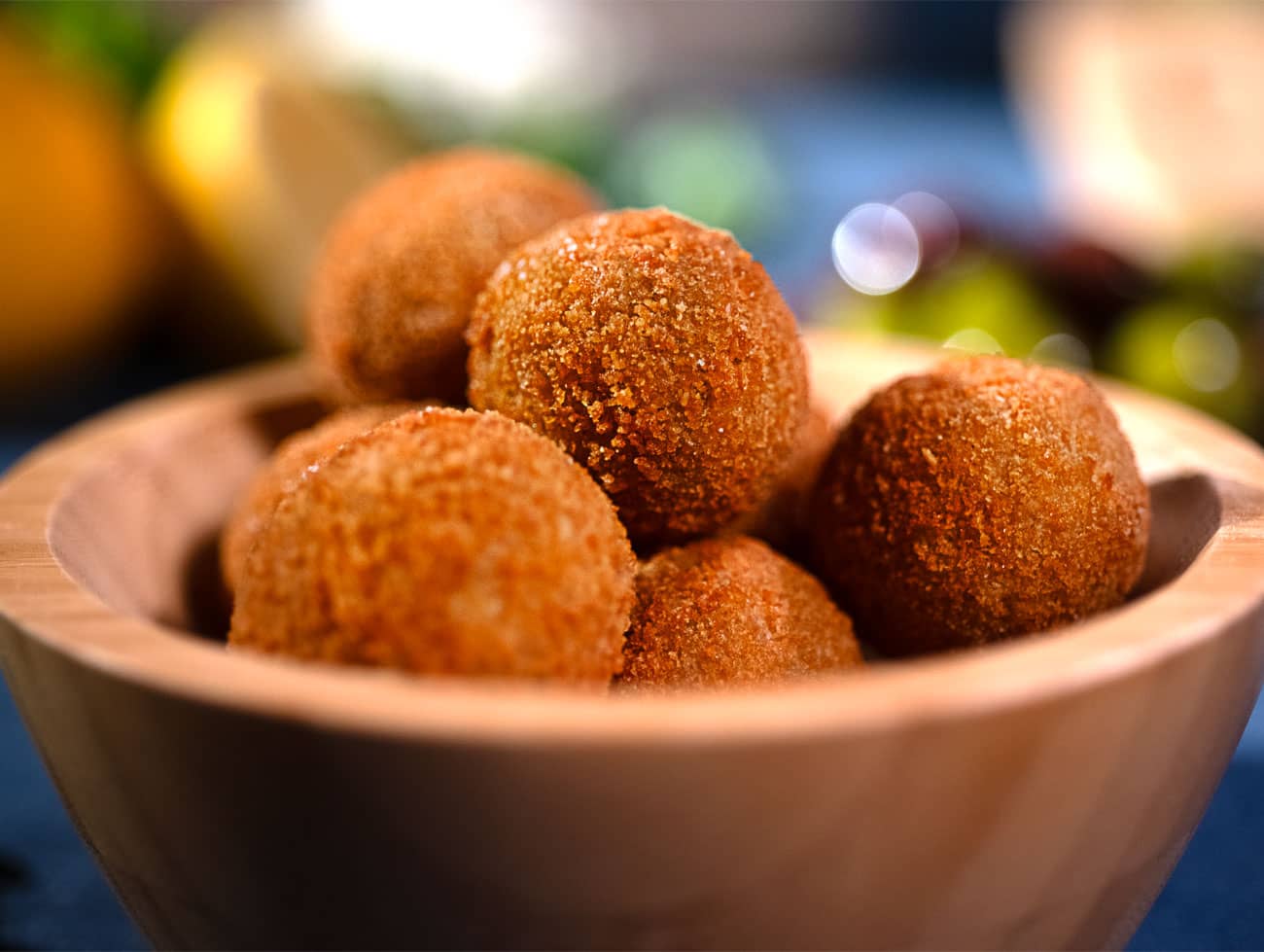 Foto del dettaglio di una piccola ciotola di legno ripiena di olive ascolane dorate e croccanti