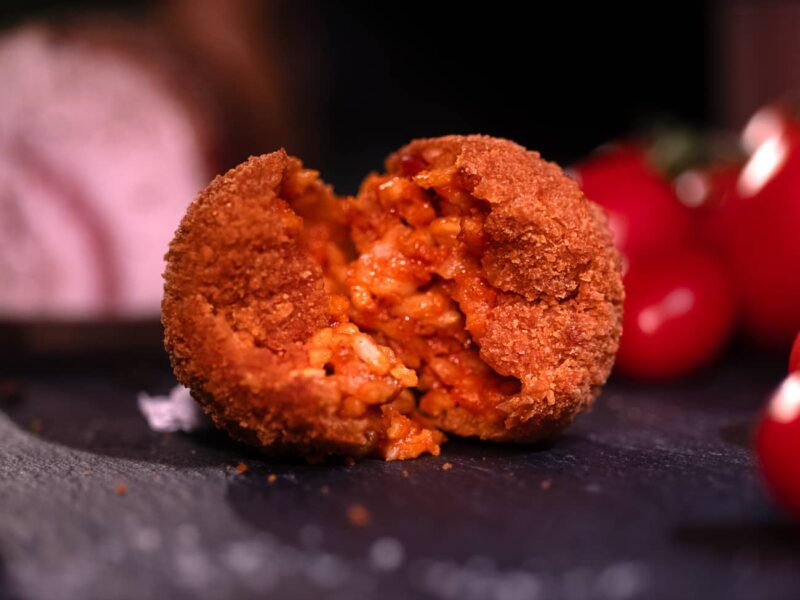 Immagine del supplì alla amatriciana aperto in due poggiato su un tavolo in ardesia